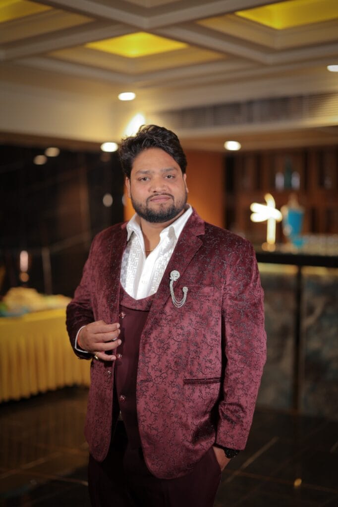 Groom posing indoors wearing a maroon textured suit.