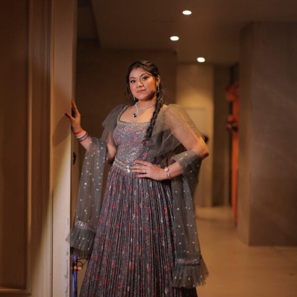 Elegant indoor photoshoot of woman wearing a grey embellished dress.