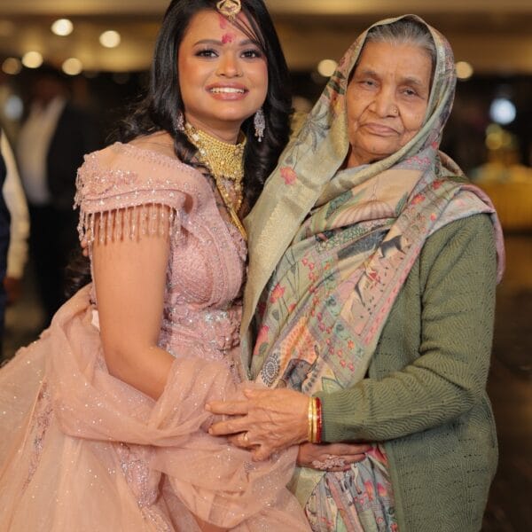 Smiling bride in pink gown standing with her grandmother at the event.