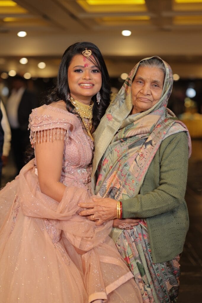 Smiling bride in pink gown standing with her grandmother at the event.